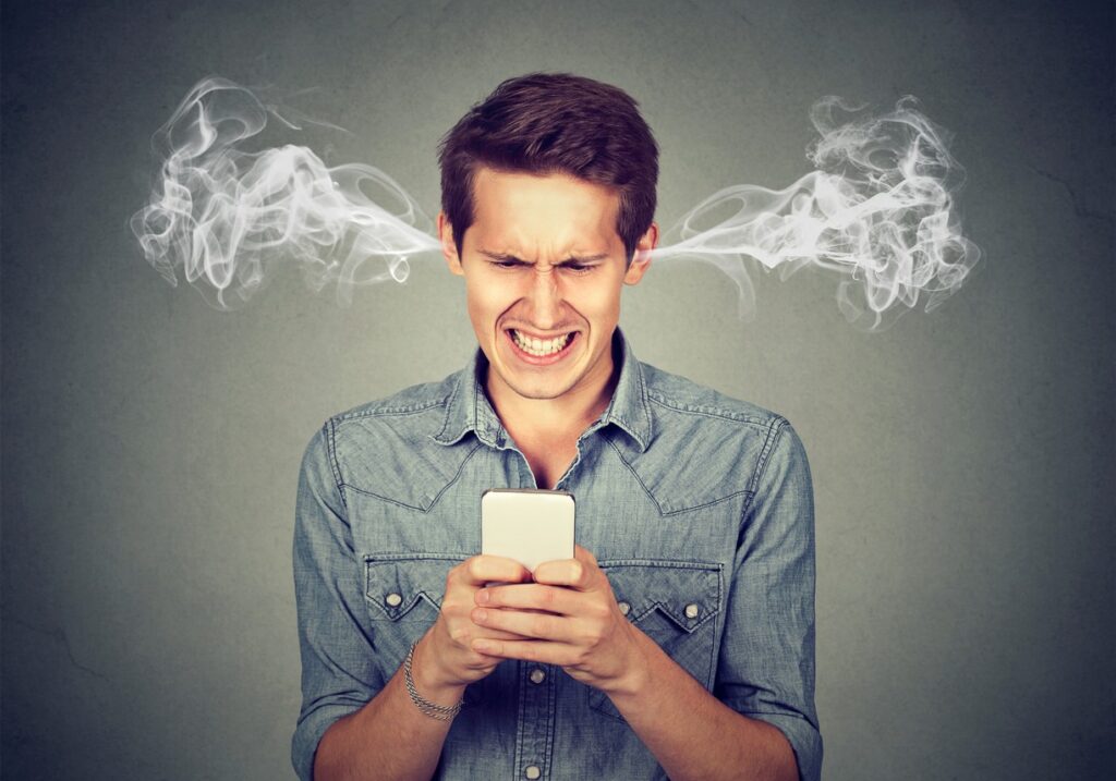 An angry man on his mobile phone with steam coming out of his ears and a frustrated look. 