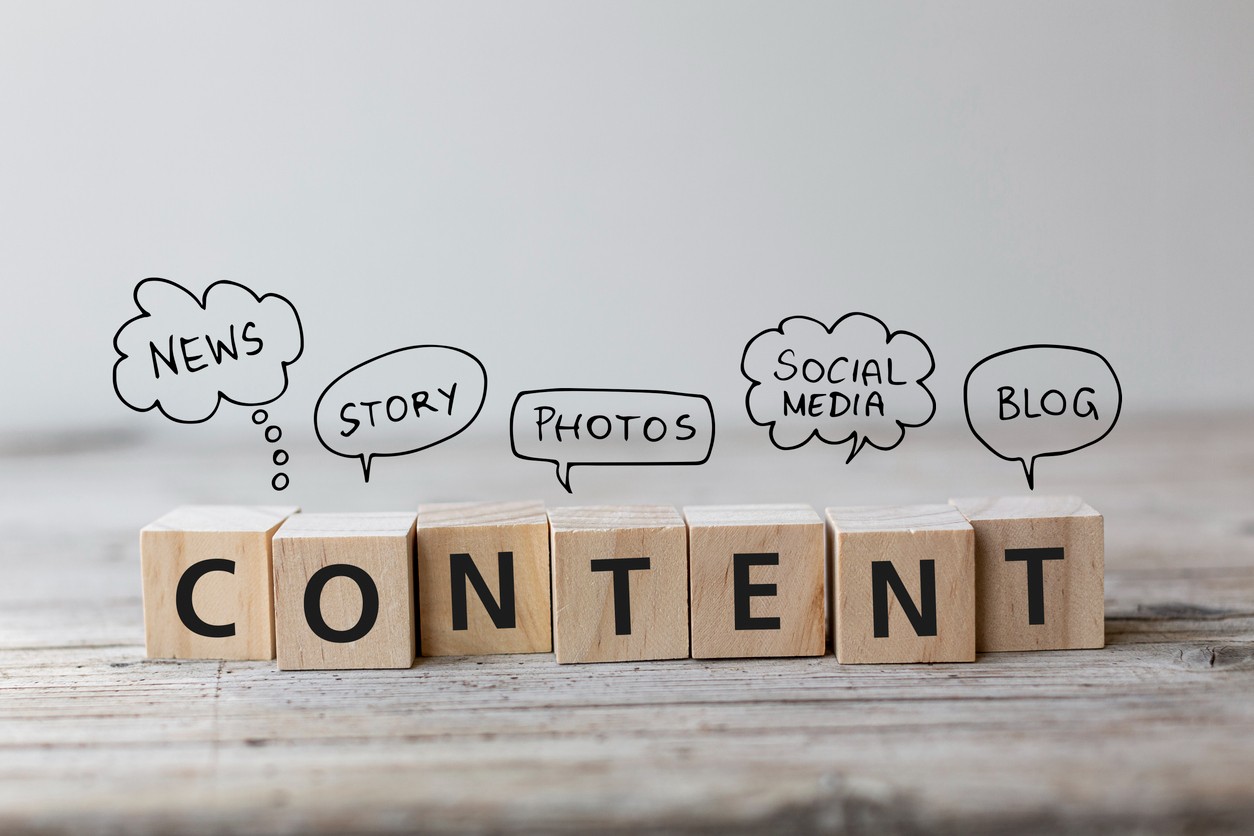 Wooden blocks spelling out the word "content" against a gray background with types of content handwritten around it.