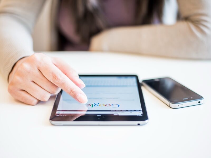 Close up view of a woman's finger pressing Google search on a tablet.