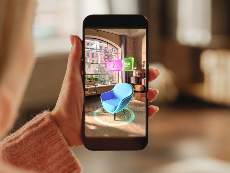 Close up of a woman looking at a chair in her living room using augmented reality on her mobile phone.