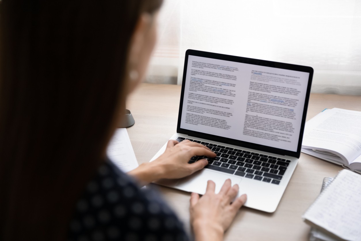 Close up of a woman drafting a blog post on a laptop using Google's E-E-A-T content guidelines.